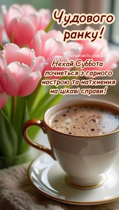Біла чашка кави з пінкою на блюдці поруч із букетом ніжно-рожевих тюльпанів та написом Чудового ранку