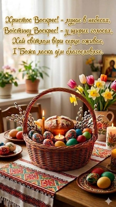 Великодній кошик з паскою, писанками та вербовими гілочками на столі з вишиваним рушником та весняними квітами