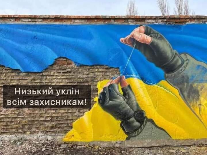 Руки українського солдата зшивають голкою розірваний украхнський прапор