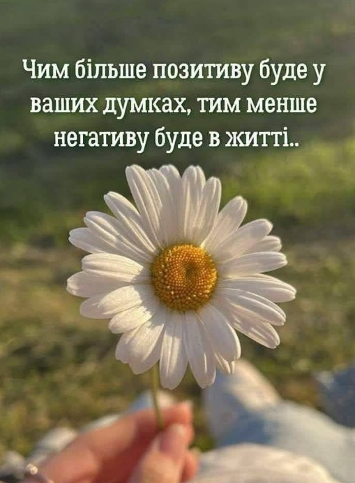 Біла ромашка в руках на фоні природи з написом про важливість позитивних думок у житті