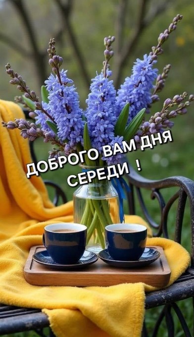 Листівка з написом Доброго вам дня середи, букетом блакитних квітів у вазі та двома чашками кави на жовтому пледі